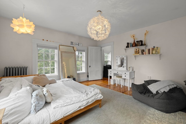 bedroom featuring radiator heating unit, multiple windows, and wood finished floors