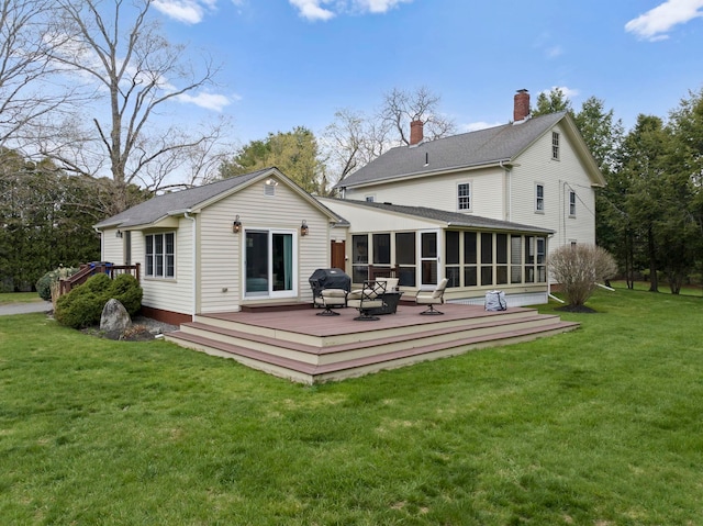back of property featuring a lawn, a wooden deck, and a sunroom