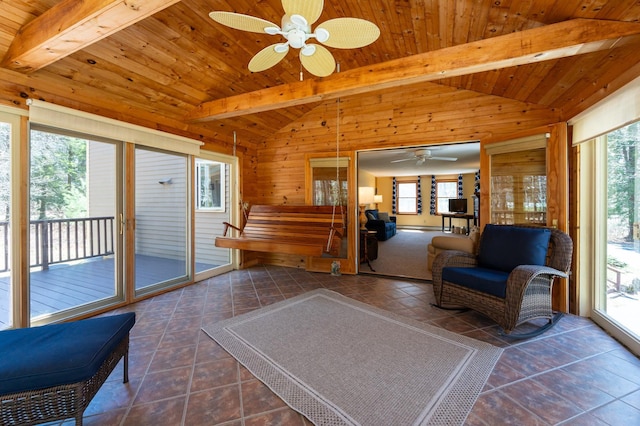 sitting room featuring wood walls, vaulted ceiling with beams, dark tile patterned floors, wooden ceiling, and a ceiling fan