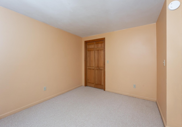 unfurnished room featuring baseboards and light colored carpet