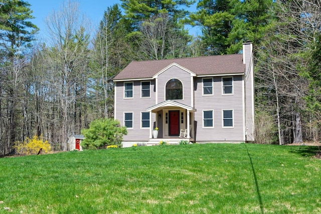 colonial-style house with a chimney and a front yard