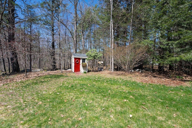 view of yard featuring an outdoor structure, a wooded view, and a shed