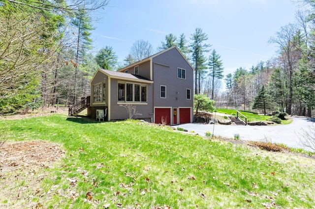 exterior space featuring an attached garage, a lawn, driveway, and stairway