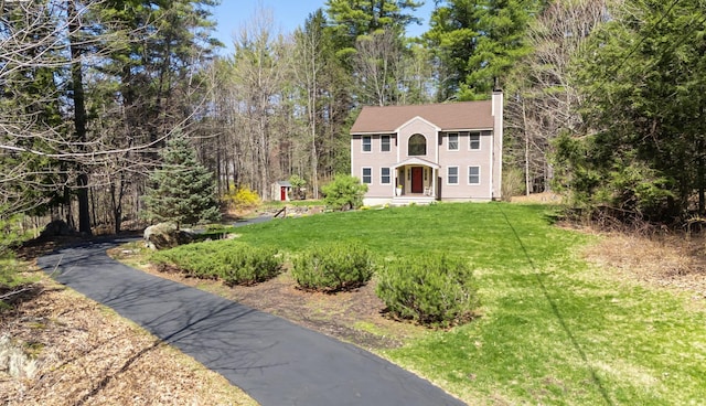 colonial-style house featuring a front yard and a chimney