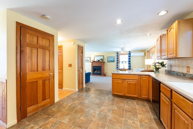 kitchen featuring light countertops, a fireplace with raised hearth, black dishwasher, a peninsula, and open floor plan