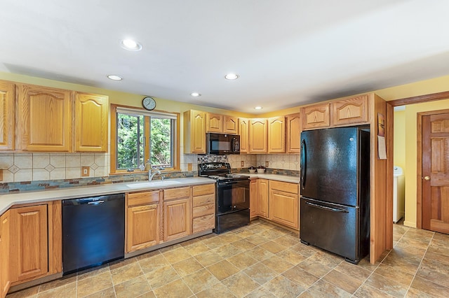 kitchen with stone finish floor, backsplash, washer / clothes dryer, a sink, and black appliances