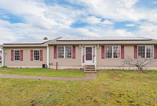 single story home featuring entry steps, central AC unit, solar panels, and a front yard