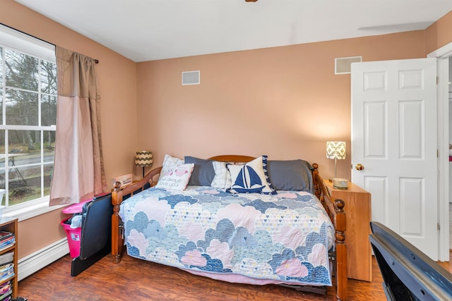 bedroom with baseboards, multiple windows, baseboard heating, and wood finished floors