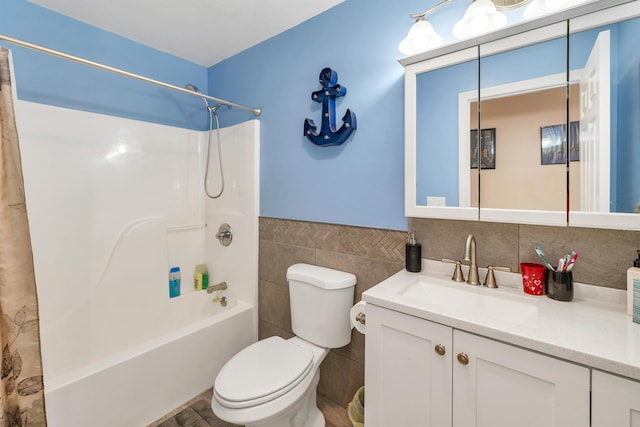 full bath with vanity, toilet, a wainscoted wall, tile walls, and tub / shower combination