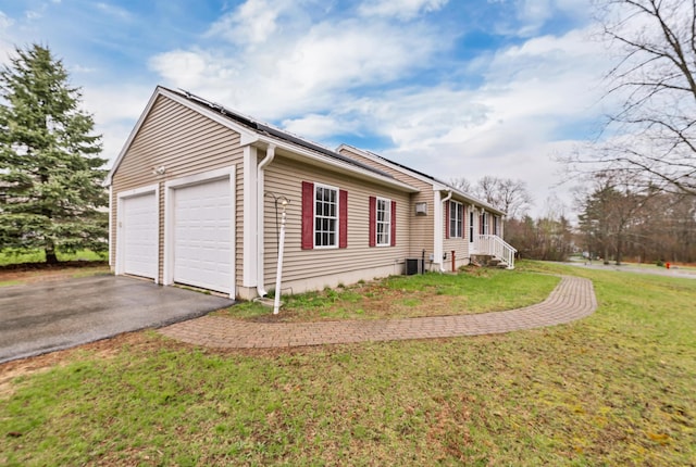 view of home's exterior featuring central air condition unit, an attached garage, a yard, and driveway