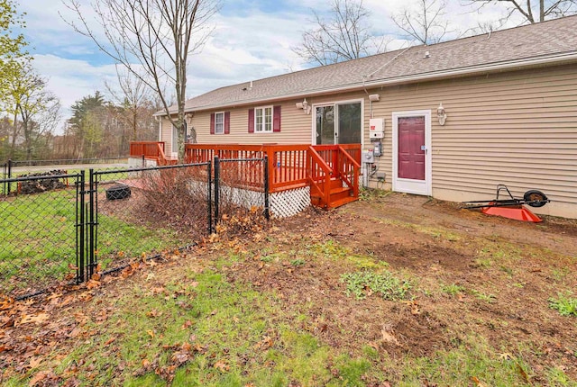 back of house featuring a lawn, a gate, fence, and a deck