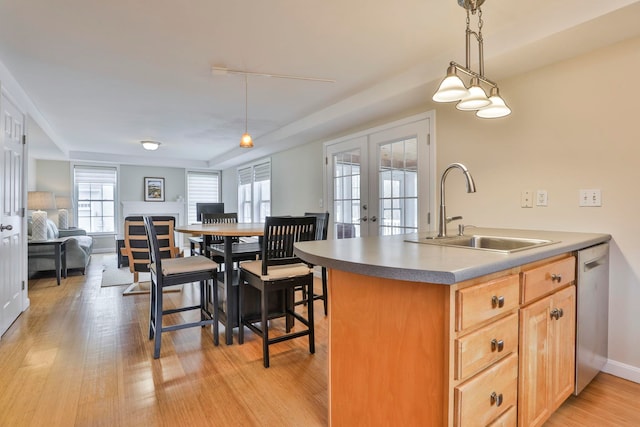 kitchen with hanging light fixtures, a sink, light wood-style floors, french doors, and stainless steel dishwasher