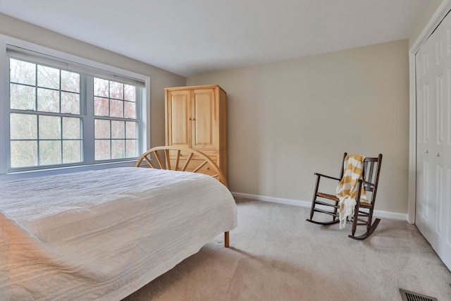bedroom with baseboards, visible vents, carpet, and a closet
