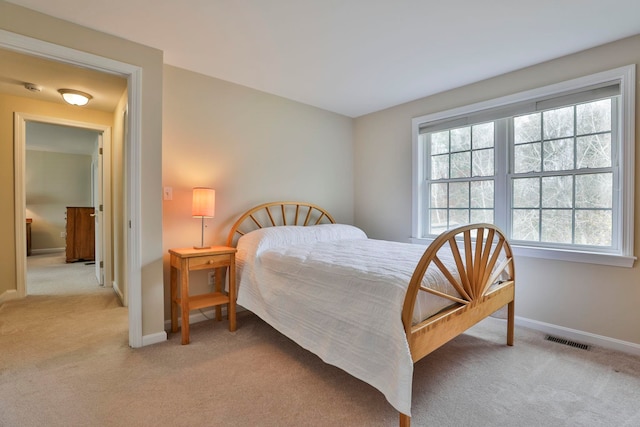 bedroom featuring baseboards, light carpet, and visible vents