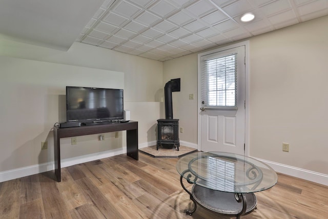 sitting room featuring baseboards, a wood stove, and wood finished floors