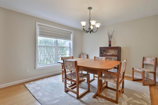 dining room with baseboards, light wood finished floors, and a chandelier