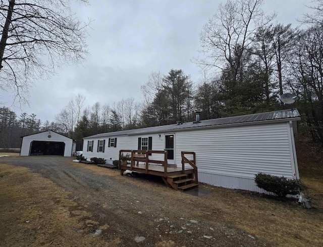 manufactured / mobile home with an outdoor structure, a garage, a wooden deck, and metal roof