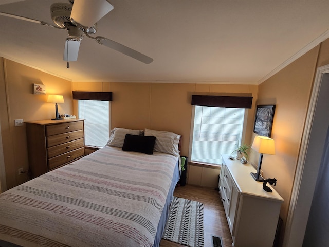 bedroom with ornamental molding, a ceiling fan, wood finished floors, and visible vents