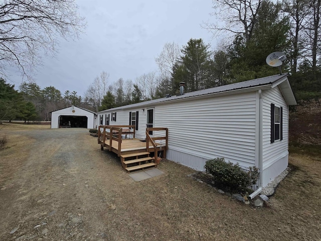 manufactured / mobile home with metal roof, a wooden deck, an outbuilding, and a detached garage