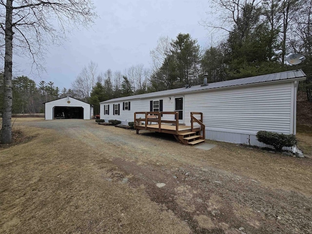 manufactured / mobile home with metal roof, a wooden deck, an outbuilding, and a detached garage