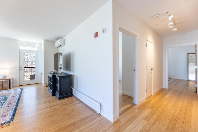 corridor with track lighting, light wood-style floors, baseboards, a baseboard heating unit, and a wall mounted AC
