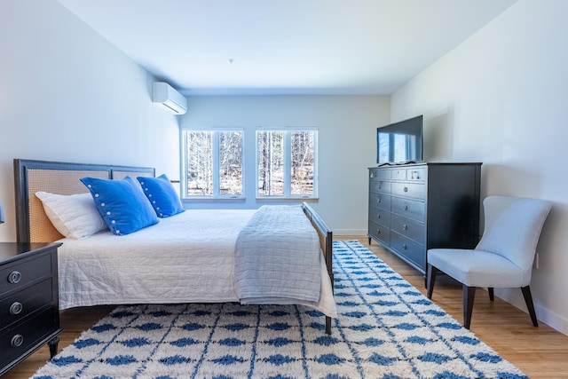 bedroom featuring baseboards, a wall mounted air conditioner, and wood finished floors