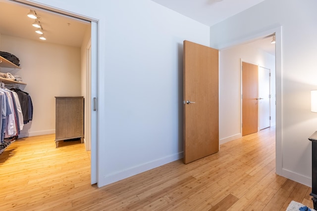 bedroom with baseboards, rail lighting, and light wood-style flooring