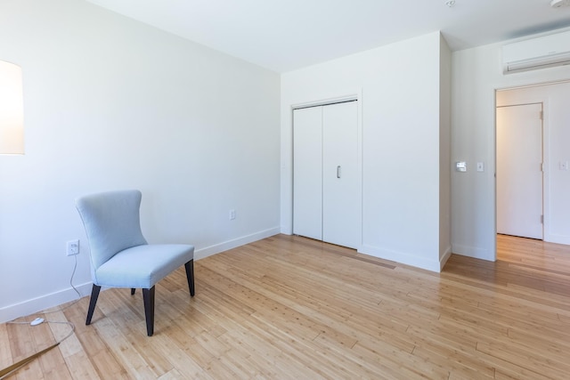 unfurnished room featuring baseboards, a wall mounted AC, and light wood-style floors