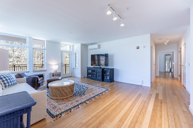 living room with baseboards, hardwood / wood-style floors, rail lighting, and a wall mounted air conditioner