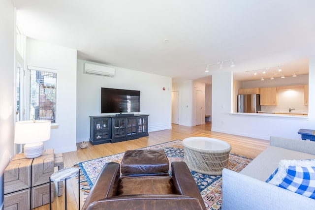 living area featuring baseboards, light wood-style flooring, and a wall mounted air conditioner