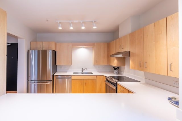 kitchen featuring light brown cabinetry, stainless steel appliances, a sink, and light countertops