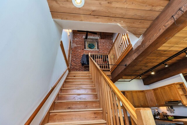 staircase with baseboards, rail lighting, and brick wall