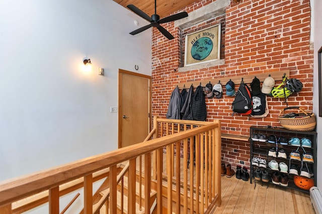 corridor with a high ceiling, a baseboard heating unit, and hardwood / wood-style flooring