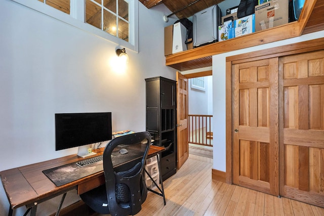 office featuring light wood finished floors and a towering ceiling