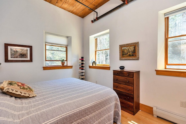 bedroom featuring a baseboard radiator, light wood-style flooring, multiple windows, and wooden ceiling