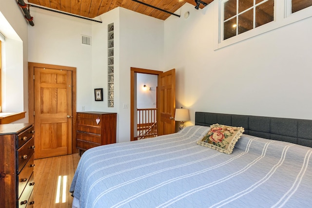 bedroom with a high ceiling, visible vents, wooden ceiling, and light wood-type flooring