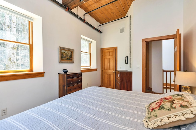 bedroom featuring visible vents, wooden ceiling, and a towering ceiling