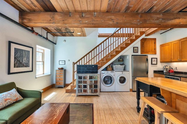clothes washing area featuring wooden ceiling, baseboards, light wood-style flooring, and independent washer and dryer