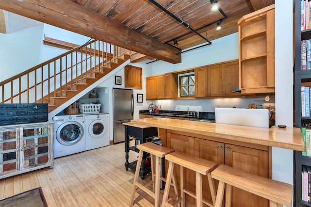 kitchen with a sink, freestanding refrigerator, butcher block countertops, and washing machine and clothes dryer