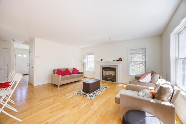 living room with light wood-type flooring, baseboards, and a fireplace
