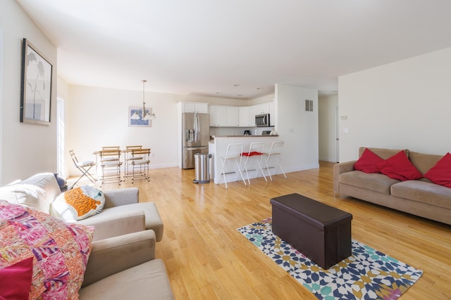 living room featuring light wood-type flooring, baseboards, and visible vents