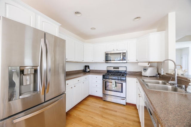 kitchen featuring white cabinets, a sink, stainless steel appliances, recessed lighting, and light wood-type flooring