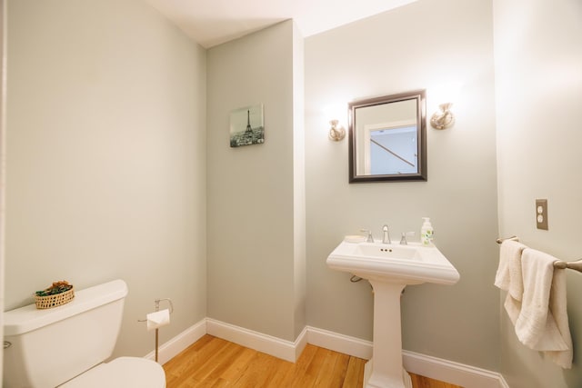 half bathroom featuring toilet, baseboards, and wood finished floors