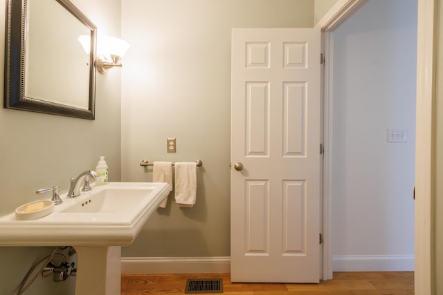 bathroom featuring baseboards, wood finished floors, and visible vents