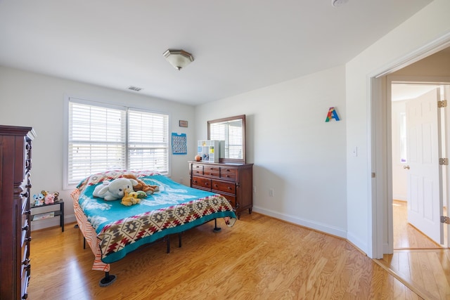bedroom with baseboards, light wood-style flooring, and visible vents
