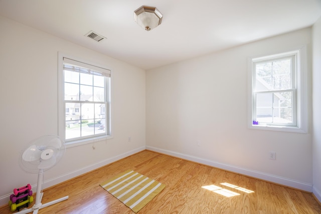 spare room with baseboards, visible vents, and light wood finished floors