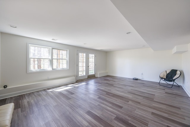 unfurnished living room with baseboards, visible vents, and wood finished floors