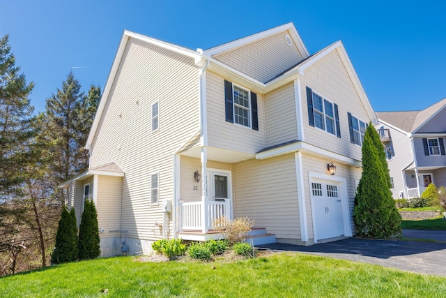 traditional-style house with a garage, a front lawn, and aphalt driveway