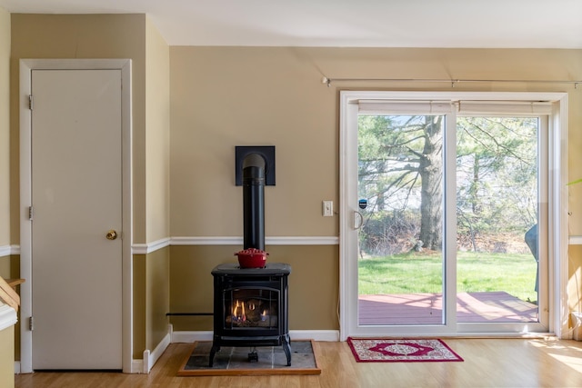 doorway with baseboards, a wealth of natural light, wood finished floors, and a wood stove