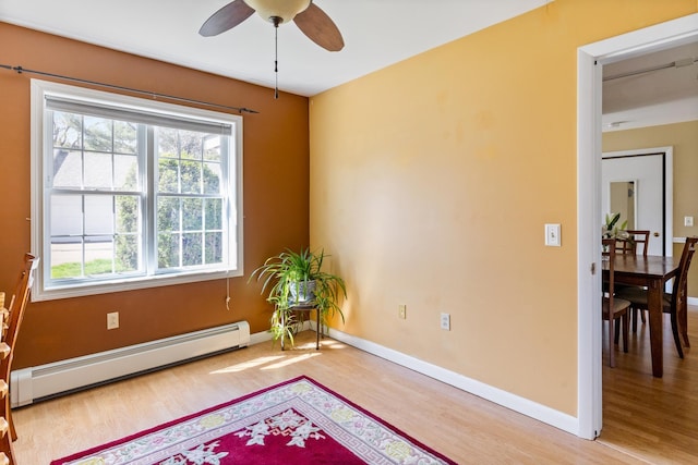 living area featuring baseboards, a baseboard radiator, a ceiling fan, and wood finished floors